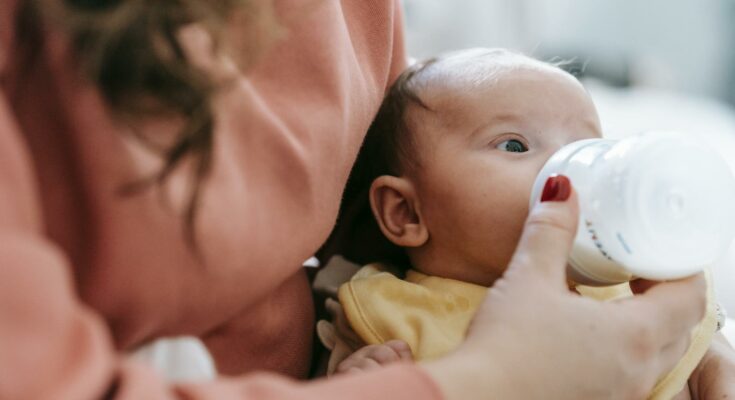 Mother feeding infant with milk from bottle