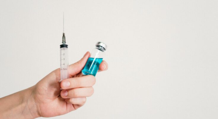 Person holding syringe and vaccine bottle
