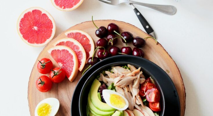 Bowl of vegetable salad and sliced fruits
