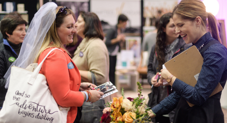 Bride-to-be enjoys speaking to florist at wedding expo