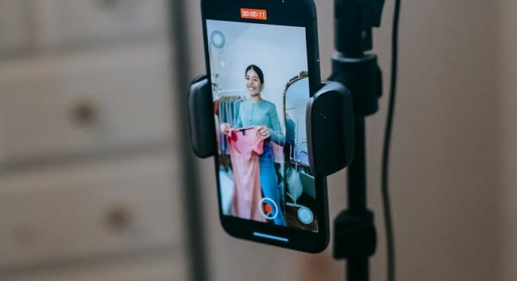 Lady filming vlog on mobile while demonstrating dress
