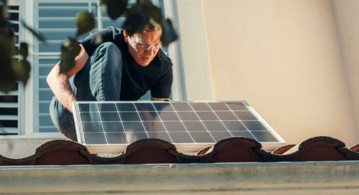 A man installing a solar panel on the roof