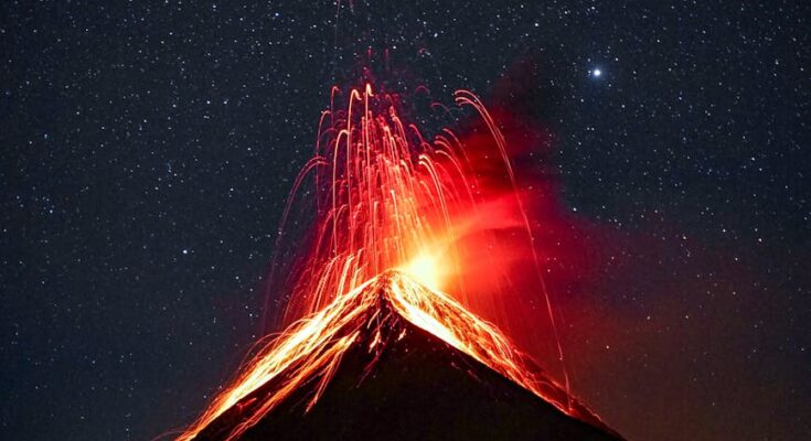 Volcano erupting at night under starry sky