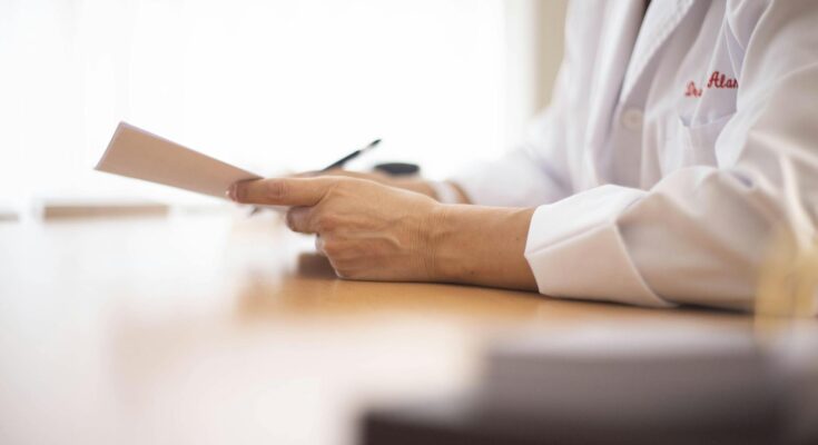 A doctor sitting at a desk and holding medical records