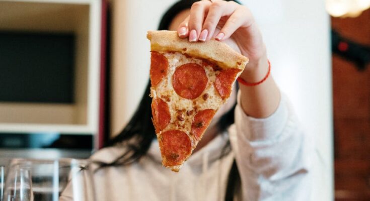 Person holding sliced of pizza