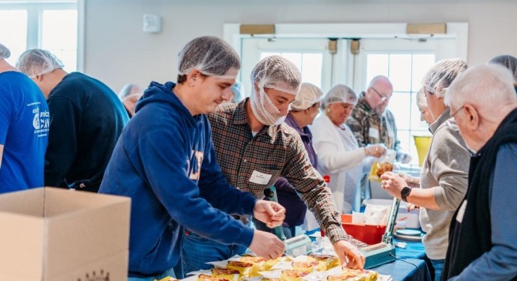 ACECO employees in an assembly line packaging food for Helping Harvest