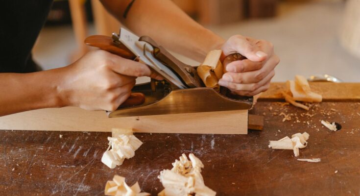 Man planing wooden plank with manual tool
