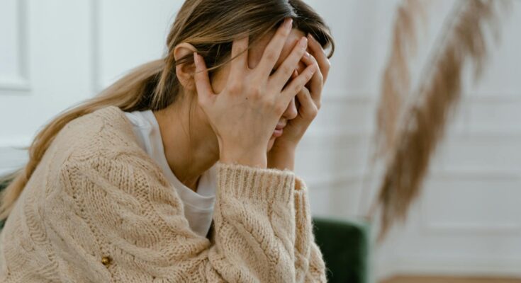 Woman sitting with hands covering her face