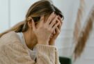 Woman sitting with hands covering her face