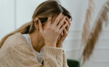 Woman sitting with hands covering her face