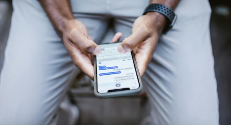 man s thumbs typing on a smartphone