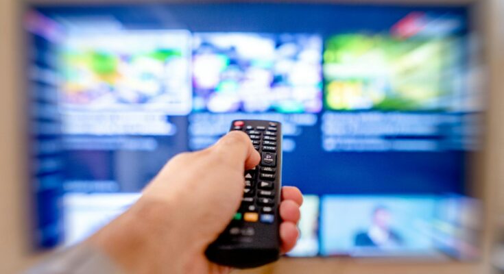 a close up shot of a person using a tv remote controller