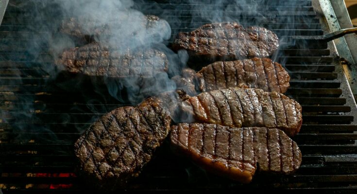 grilled beef steaks with smoke on barbecue grill