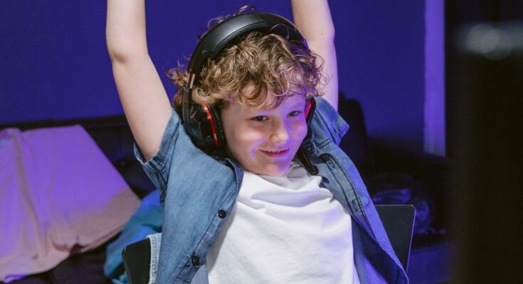 a boy sitting in front of a computer winning a computer game