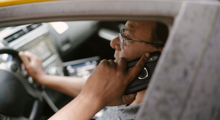 ethnic man chatting on smartphone in car