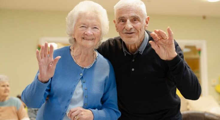 Elderly couple waving and smiling at the camera