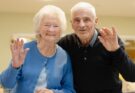 Elderly couple waving and smiling at the camera
