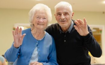 Elderly couple waving and smiling at the camera