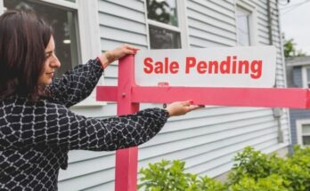 A realtor adjusting a sale pending sign outside a house for sale.