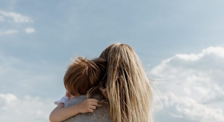 woman holding child from behind against cloudy sky