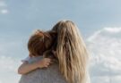 woman holding child from behind against cloudy sky