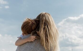woman holding child from behind against cloudy sky