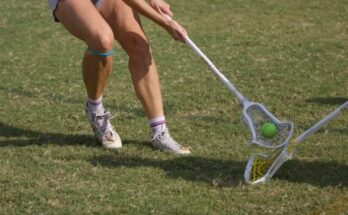 Woman playing lacrosse on a grassy field
