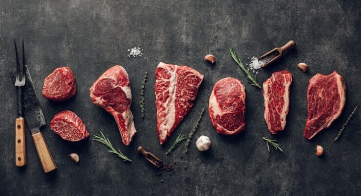 raw meat on a table with a knife, garlic and pepper