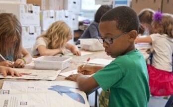 boy in green sweater writing on white paper