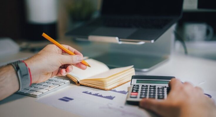 a person sitting at a desk with a calculator and a notebook