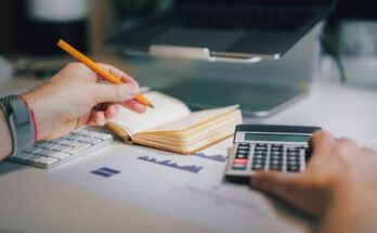 a person sitting at a desk with a calculator and a notebook