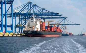 a large cargo ship in the water with a large crane in the background