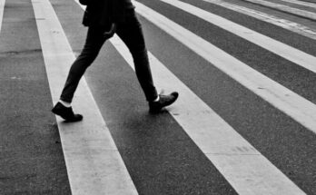 person in black pants and black sneakers walking on pedestrian lane