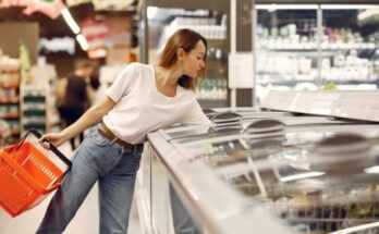 young woman picking food from showcase fridge