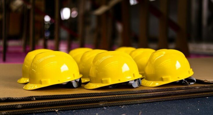 Several bright yellow hard hats are neatly lined up