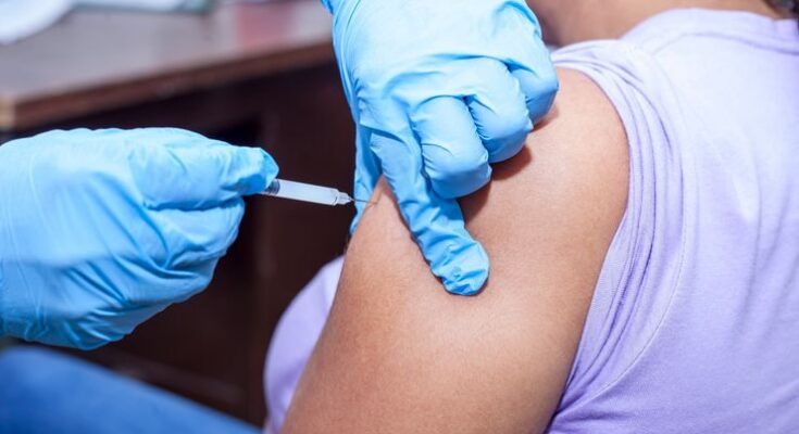 Close-up shot of a healthcare professional giving a vaccine injection.