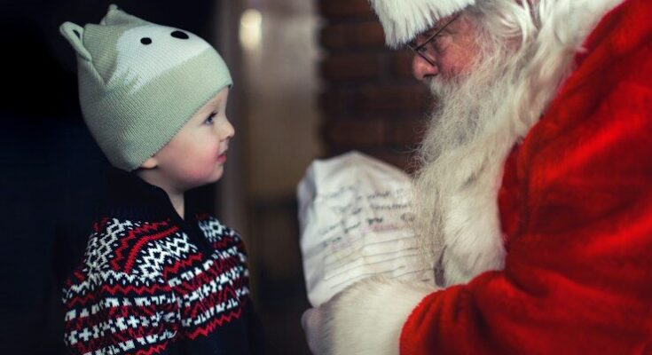 toddler in black sweater standing in front of Santa Claus