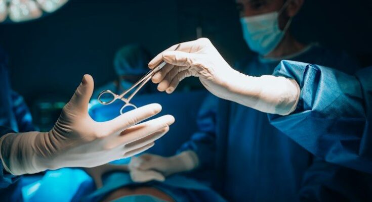 a person in a surgical gown is holding a pair of scissors