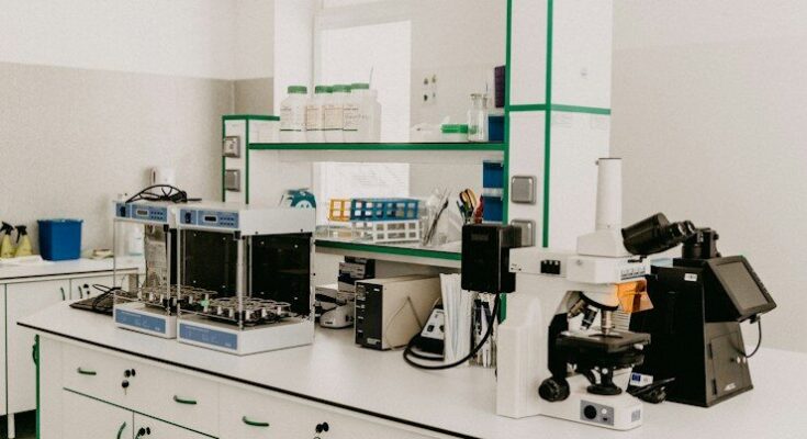 A laboratory workbench with a microscope and analytical equipment in a bright room