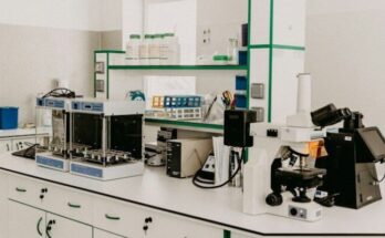 A laboratory workbench with a microscope and analytical equipment in a bright room