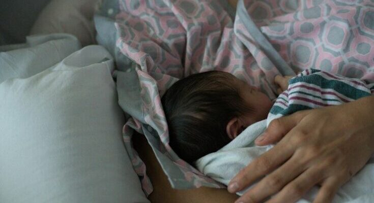 Mother holding a newborn baby while breastfeeding